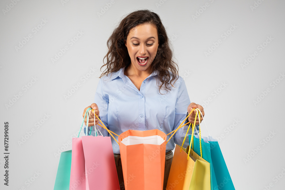 Shocked glad millennial european lady in formal wear with open mouth look at many shopping bags Shocked glad millennial european lady in formal wear with open mouth look at many shopping bags