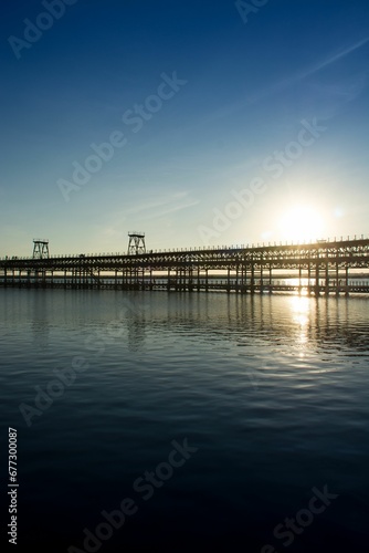 Vertical of Rio Tinto pier in Huelva, Spain across the scenic Atlantic ocean against the sunset sky