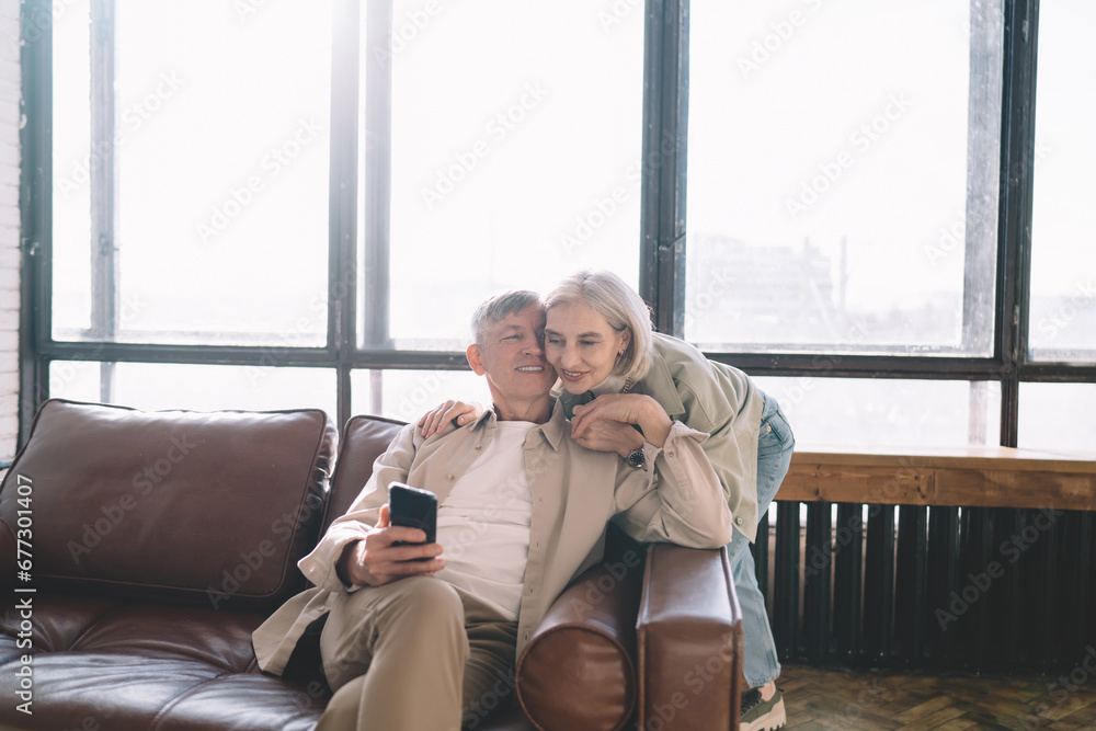 Obraz premium Senior couple using smartphone on sofa