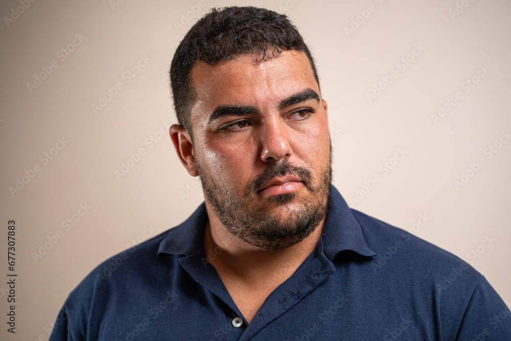 Man with dark hair and beard looking to the side with serious expression on pastel background. Man with dark hair and beard looking to the side with serious expression on pastel background.