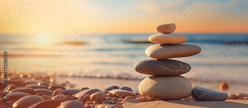 Balanced rock pyramid on pebbled beach with golden sea bokeh Zen stones on sea beach conveying meditation spa harmony and balance Copy space image Place for adding text or design photo