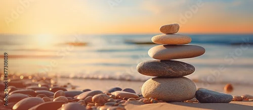 Panel kuchenny z motywem Balanced rock pyramid on pebbled beach with golden sea bokeh Zen stones on sea beach conveying meditation spa harmony and balance Copy space image Place for adding text or design