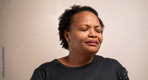 Black woman with eyes closed with sad expression on pastel background. photo