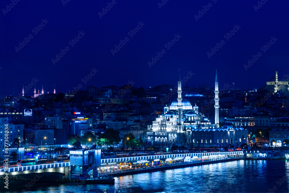 Beautiful night time view of Istanbul's historical peninsula skyline with the New Mosque and famous Galata Bridge