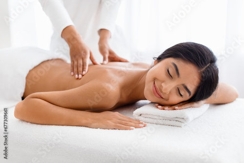 Indian woman enjoying relaxing back massage in spa