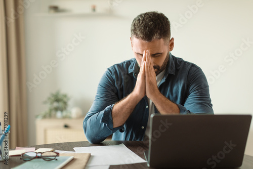 worried middle aged man at laptop suffering from stress indoor