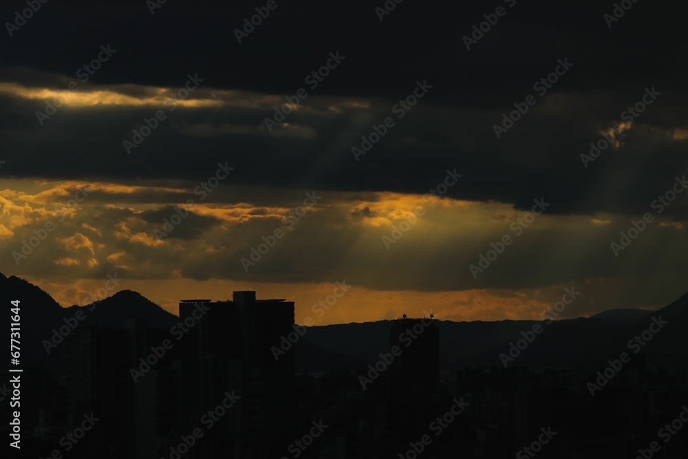 Silhouette shot of buildings and mountains during sunset