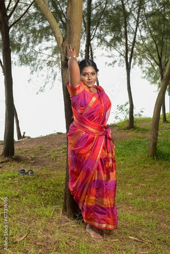 Vertical of a South Asian female in Malaysian traditional dress posing in a forest