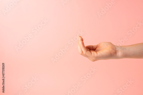 Open hand as if taking some object on pink background. Copy space