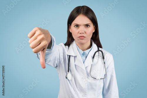 Stern female doctor giving thumbs down gesture photo