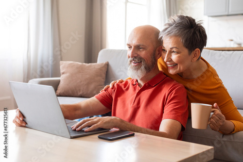 Tech-Savvy Seniors. Happy Older Couple Using Laptop Together At Home photo