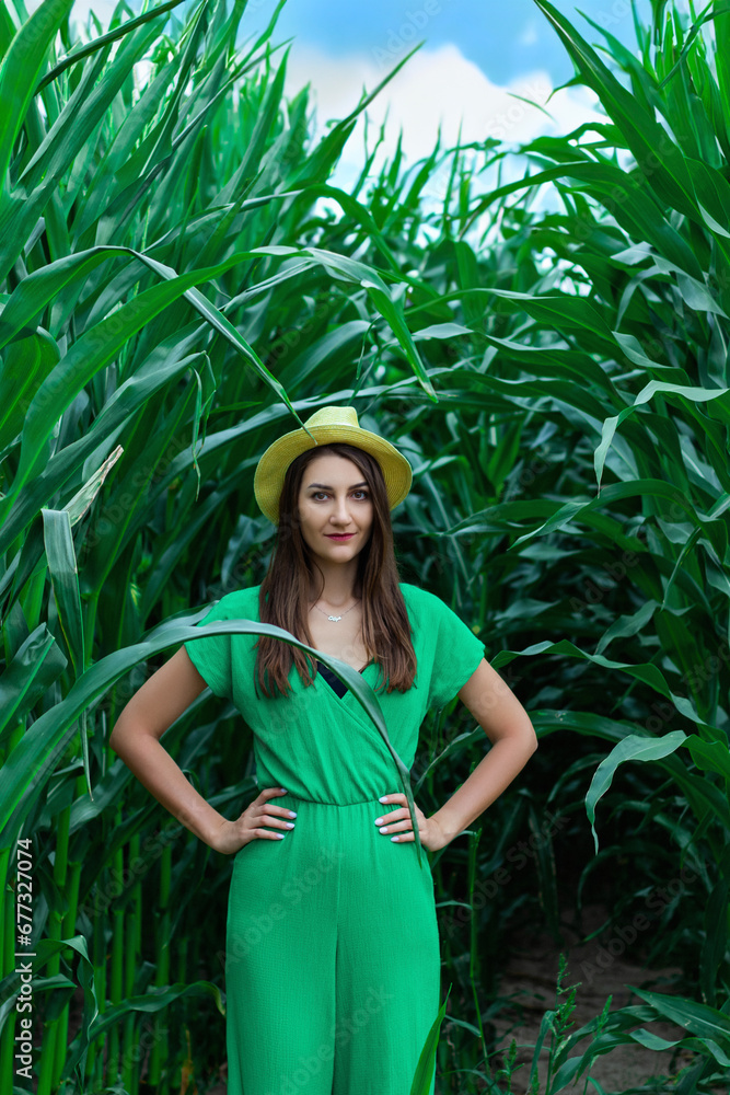 Young pretty woman in the yellow hat among the corn plants in the corn field in summer season. Bereza, Belarus Young pretty woman in the yellow hat among the corn plants in the corn field in summer season. Bereza, Belarus