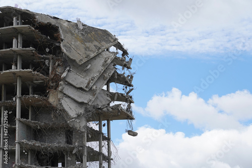 Industrial demolition of a multi-storey building, a building with collapsed floors against a blue sky with clouds