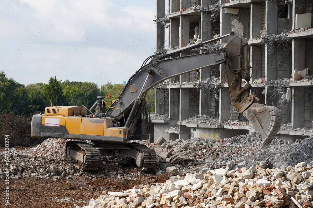Fototapeta premium Building destruction, demolition of a building by an yellow excavator