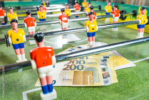 Table football game with euro bills scattered around plastic players, concept of manipulated paid matches
