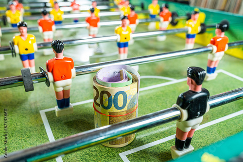 Table football game with rolled up euro bank notes in front of plastic goal keeper, concept of betting and victory, investment in sports