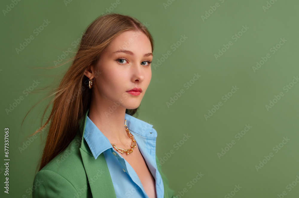 Fashionable beautiful confident woman wearing trendy golden hoop earrings, chain necklace, blue shirt, green suit blazer. Close up studio portrait. Copy, empty space for text Fashionable beautiful confident woman wearing trendy golden hoop earrings, chain necklace, blue shirt, green suit blazer. Close up studio portrait. Copy, empty space for text