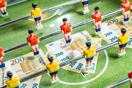 Table football game with euro bills scattered under figures of the players, concept of betting and gambling