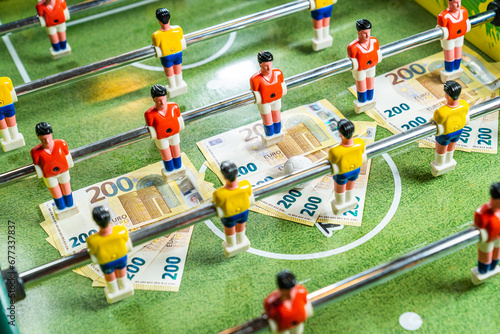 Table football game with euro bills placed under yellow and red plastic players, concept of gambling and money debts
