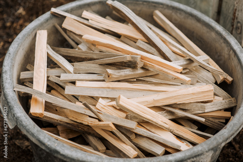 A large pile of firewood, chopped planks of wood lie in a bowl outdoors in the forest. Close-up nature photography.