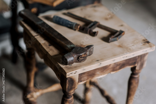 Locksmith tools, a hammer and a clamp lie on a wooden chair in the workshop. Photography, industry concept.