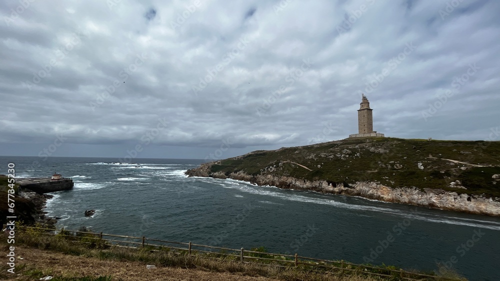 panoramic view of the tower of hercules in la acoruña, spain. dark stormy sky and surrounding nature. You can see the surrounding beach