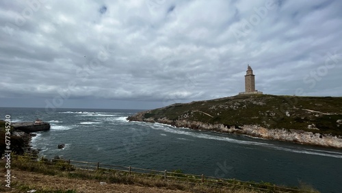 panoramic view of the tower of hercules in la acoruña, spain. dark stormy sky and surrounding nature. You can see the surrounding beach