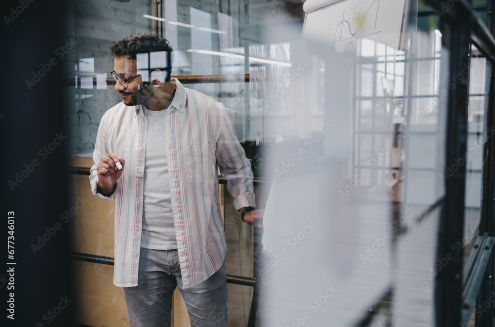 Through glass view of stylish Hispanic man working in modern office