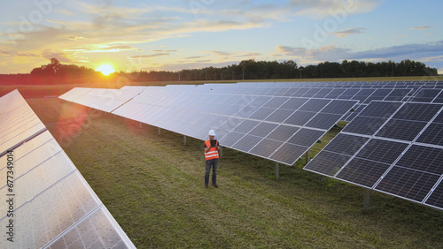 Aerial: engineer analysing solar farm energy production, modern job concept photo