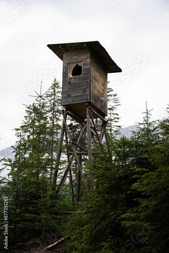 Vertical shot of a birdhouse surrounded by trees with a sky in the background in Dolomites © Wirestock