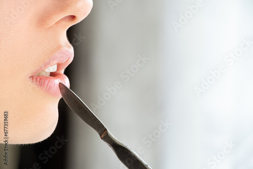 Surgical scalpel near the girl's face on the lips, beauty and fashion, surgery, lips photo