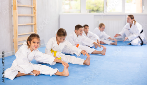 Young karate students engage in stretching exercises to improve their flexibility and balance.