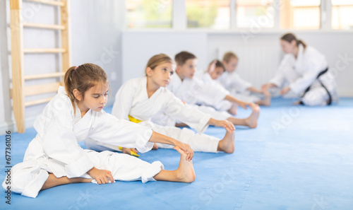 Young karate students engage in stretching exercises to improve their flexibility and balance.