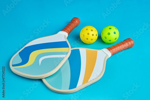two pickleball paddles in blue tones on a blue surface with two balls next to it