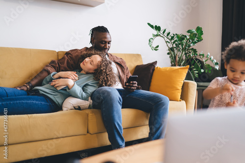 Positive multiethnic couple with daughter spending time together in living room