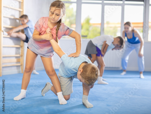 Kids practice grabbing their opponent's arms and taking them down in controlled manner.