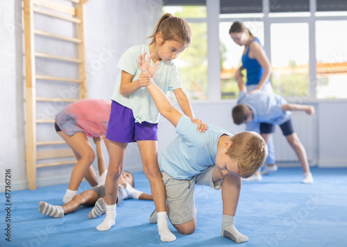 Young children, boy and girl, working in pair mastering new self-defense moves at gym