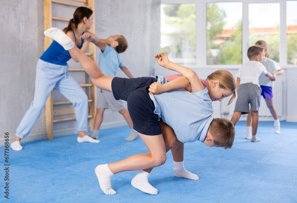 Fototapeta premium Children train in pairs to strike and reflect blows of enemy. Self-defense training and Krav Maga principles