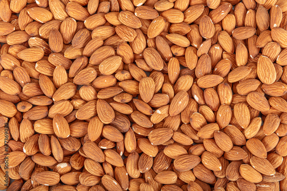 Close-up view of raw almonds without shells from above. Close-up raw brown almond seeds in copper bowl isolated on white background. Top view. It was lying flat. Close-up view of raw almonds without shells from above. Close-up raw brown almond seeds in copper bowl isolated on white background. Top view. It was lying flat.