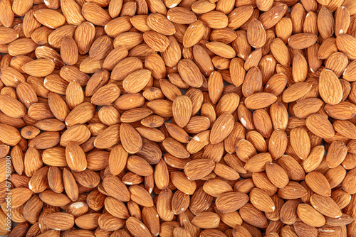 Close-up view of raw almonds without shells from above. Close-up raw brown almond seeds in copper bowl isolated on white background. Top view. It was lying flat.