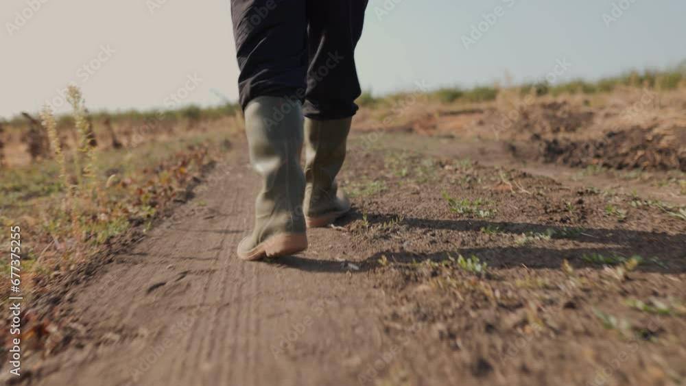 Close Up View of a Farmer Boots and Legs Treading the Country Road, an Illustration of Agrarian Life in Motion. In the Footsteps of Agriculture A Farmer Rubber Boots on a Country Road, tracking shot Close Up View of a Farmer Boots and Legs Treading the Country Road, an Illustration of Agrarian Life in Motion. In the Footsteps of Agriculture A Farmer Rubber Boots on a Country Road, tracking shot