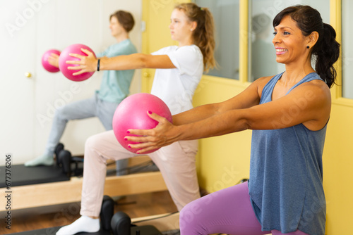 Positive woman pilates instructor with teenagers engaged in gym
