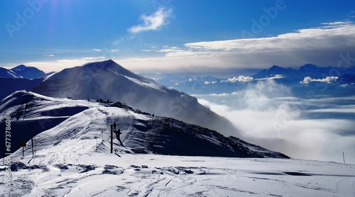 Beautiful view of a snowy mountain with people doing ski against blue cloudy sky