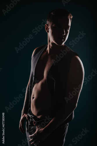 Fit man flexing muscles, showcasing results of body transformation in studio silhouette against black background. © qunica.com