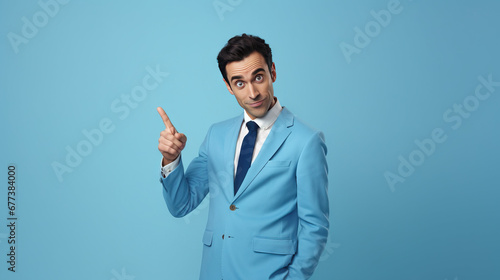 Portrait of confident salesman pointing at product with copy space while standing on blue background
