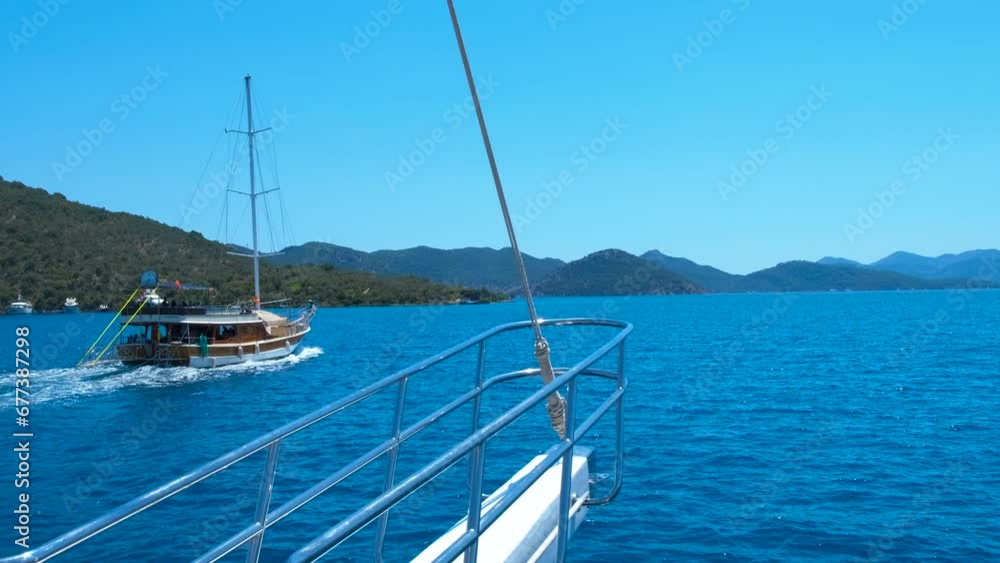 Yacht sailing against gorgeous coast. Tourists floating on yachts and making waves on the blue sea against nature landscape in summer.