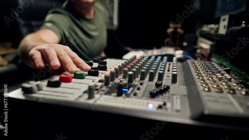 A close-up of a mixing console device used by a man working as professional sound engineer in a music studio photo