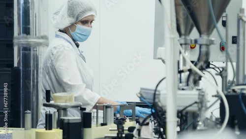 Worker is standing at the end of conveyor line at food production facility. Worker is collecting the food after the production. Worker is dealing with the storage of food items in at production plant. photo