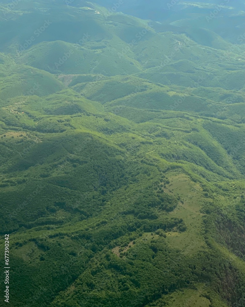 Vertical aerial view of lush green meadow with hills