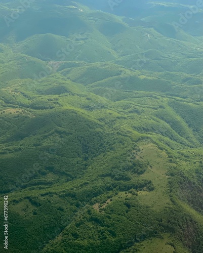Vertical aerial view of lush green meadow with hills © Wirestock
